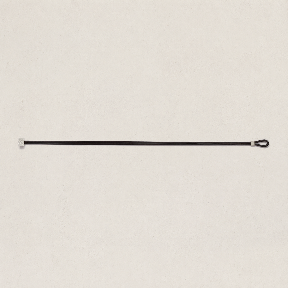 A minimalist black leather strap with silver metal hardware, displayed horizontally against a textured off-white background.